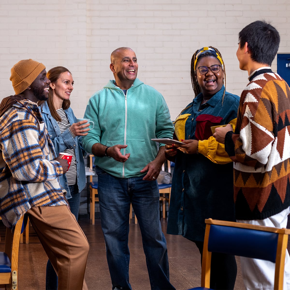 Group of adults laugh and drink coffee