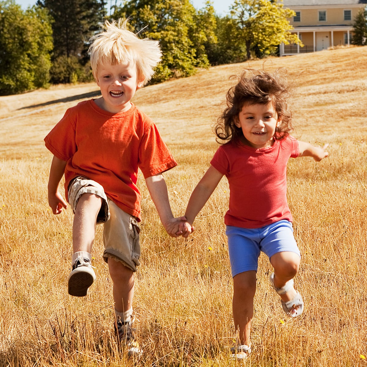 Two kids frolic in the grass